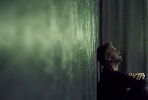 Man sitting against the wall with his head back