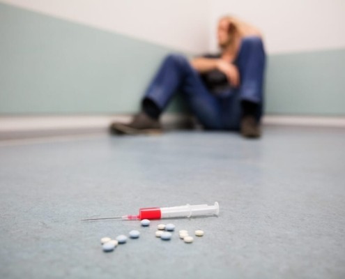 what percentage of addicts stay clean- Man against a wall with pills and a needle on the ground