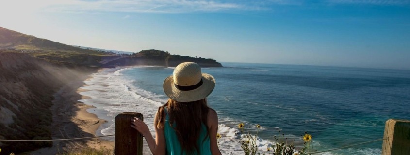 Young woman overlooking the ocean/beach wearing a hat